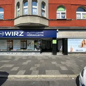 Fassade eines Augenoptik- und Hörakustik-Fachgeschäfts mit Werbeplakat und Auslage.