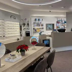 Modernes Optiker-Geschäft mit Brillenauswahl, Beratungstisch und Verkaufsbereich.