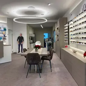 Modernes Optiker-Geschäft mit Brillenregalen, Beratungstisch und stilvoller Beleuchtung.